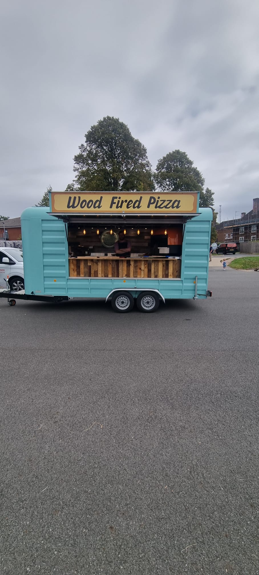The South Coast Pizzas teal wood-fired pizza trailer with its hatch open